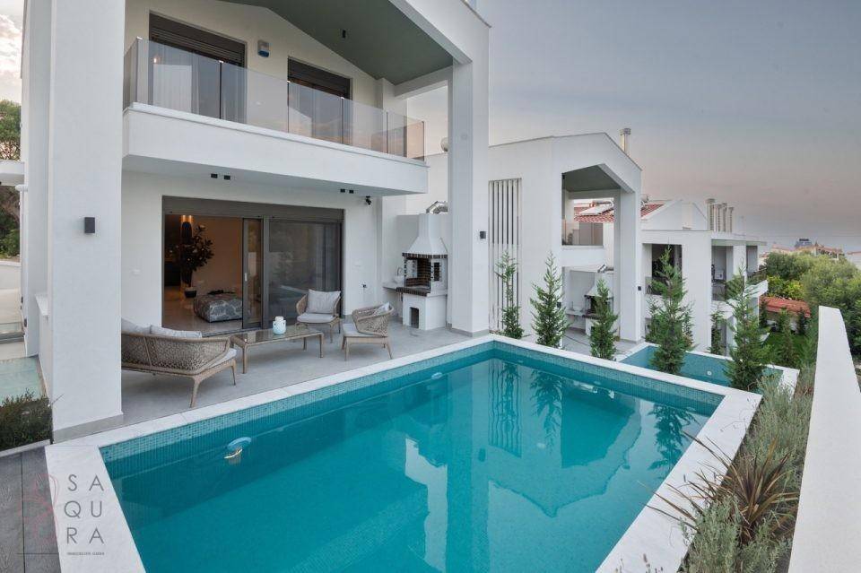 Weitläufige Außenansicht der modernen Villa mit Pool und umliegender Bebauung.