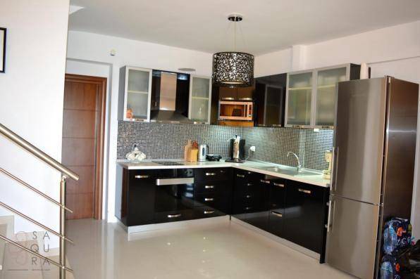 Moderne Küche mit schwarzen Hochglanzschränken, Mosaikfliesen und Edelstahlgeräten.