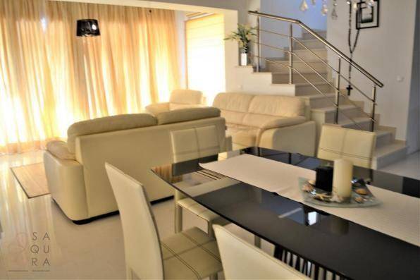 Offener Wohn- und Essbereich mit Treppe, beigen Ledersofas und modernem Dekor.