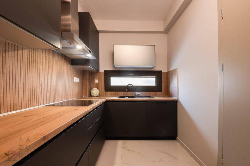 Elegante Küche mit dunklen Schränken, Holz-Arbeitsplatten und integrierten modernen Geräten.