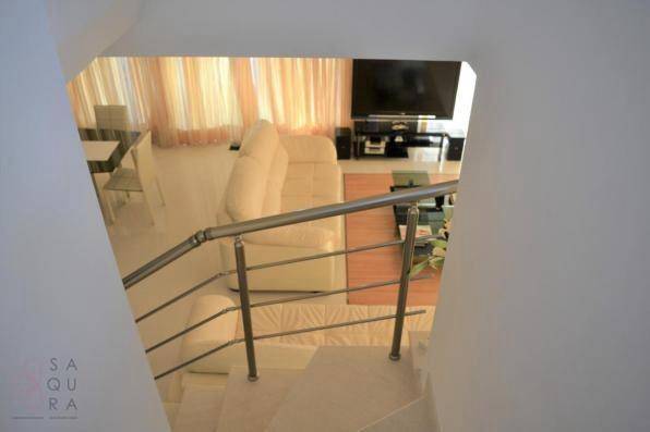 Blick von der Treppe in den hellen Wohnbereich mit beigen Sofas und großem Fernseher.