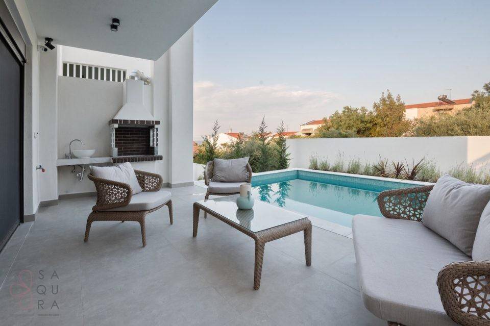 Stilvolle Terrasse mit bequemen Sitzgelegenheiten, Grillbereich und Blick auf den Pool.