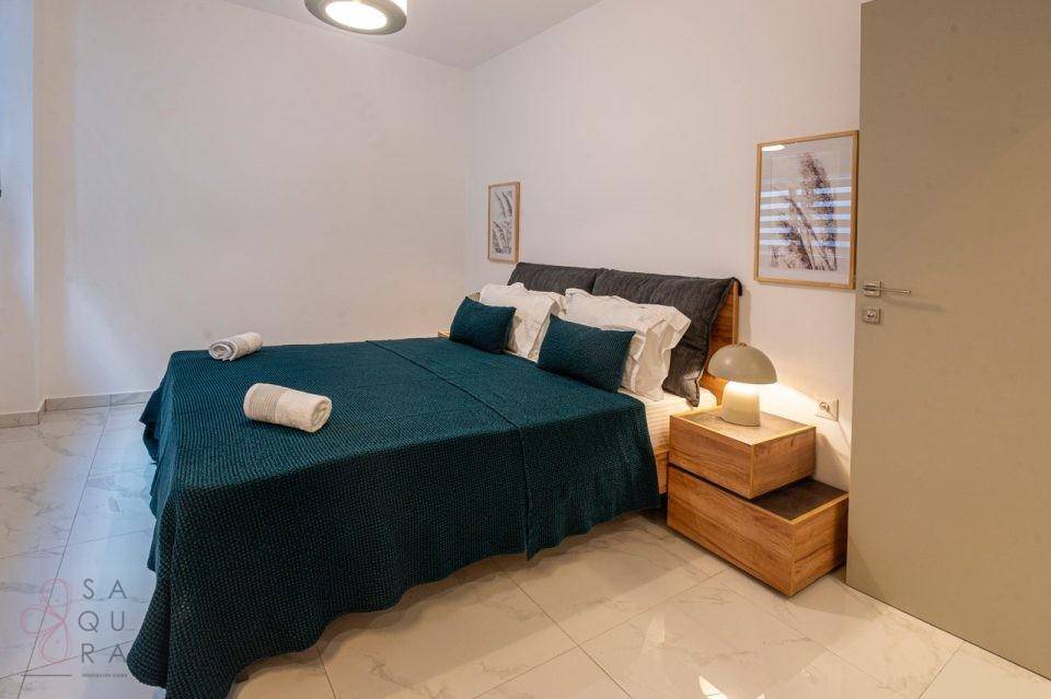 Ruhiges Schlafzimmer mit Doppelbett, dunkler Bettwäsche und minimalistischer Einrichtung.