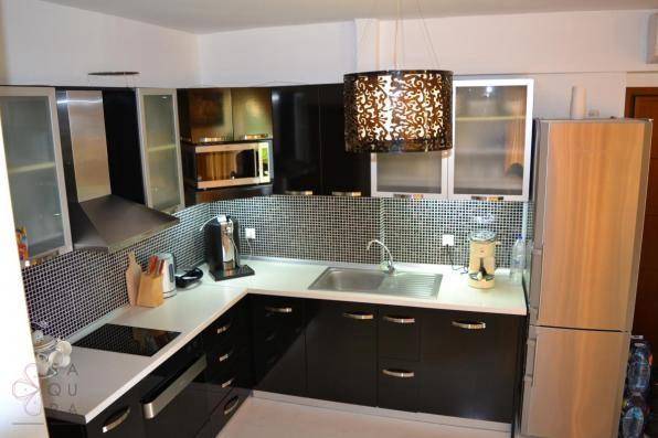 Moderne Küche mit schwarzen Hochglanzschränken, Mosaikfliesen und Edelstahlgeräten.