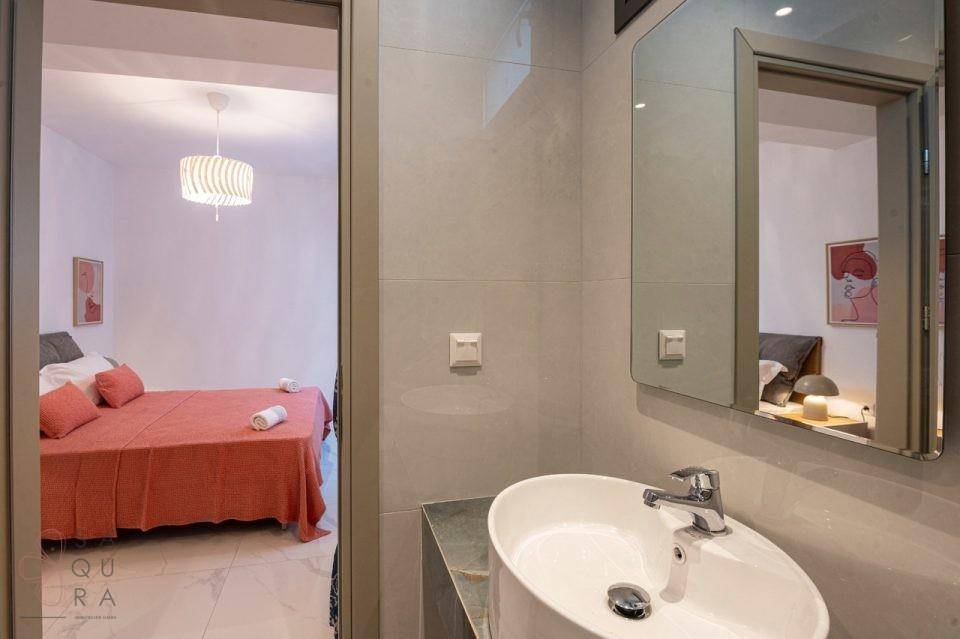Modernes Badezimmer mit ovalem Waschbecken und Blick in ein angrenzendes Schlafzimmer.