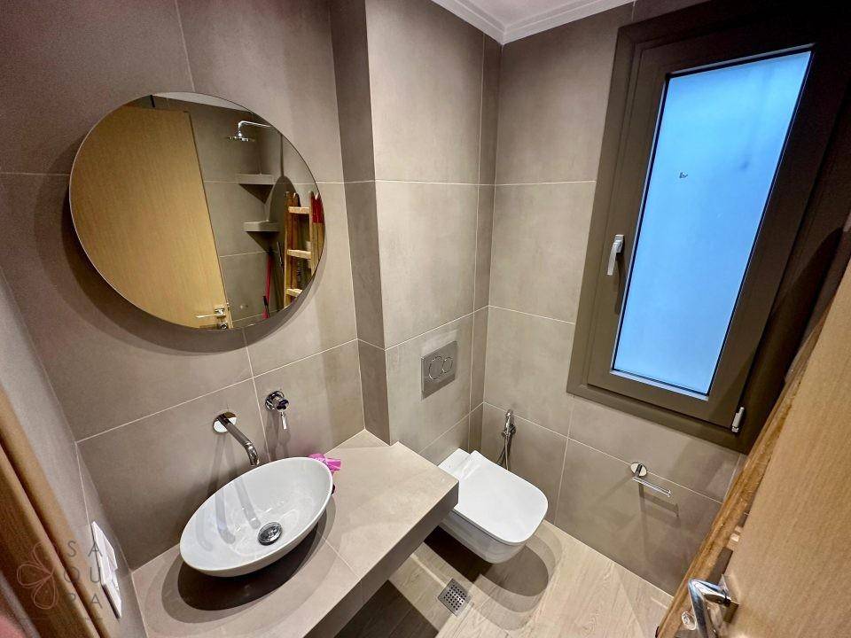 Modernes Gäste-WC mit Wand-WC, Aufsatzwaschbecken und Fenster.