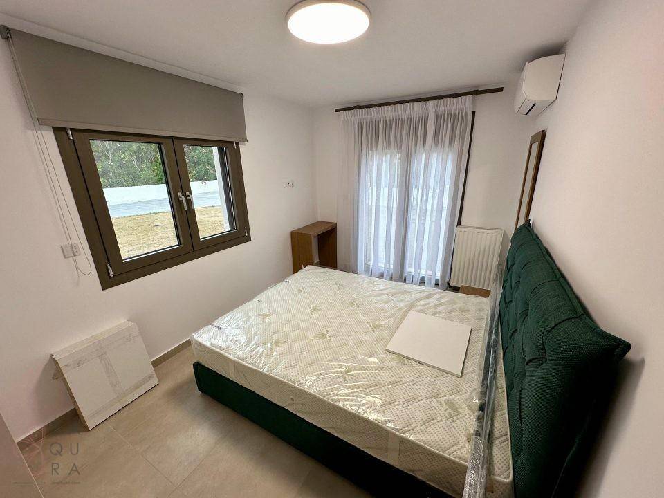 Helles Schlafzimmer mit Doppelbett, Fliesenboden und Fenster mit Blick ins Freie.