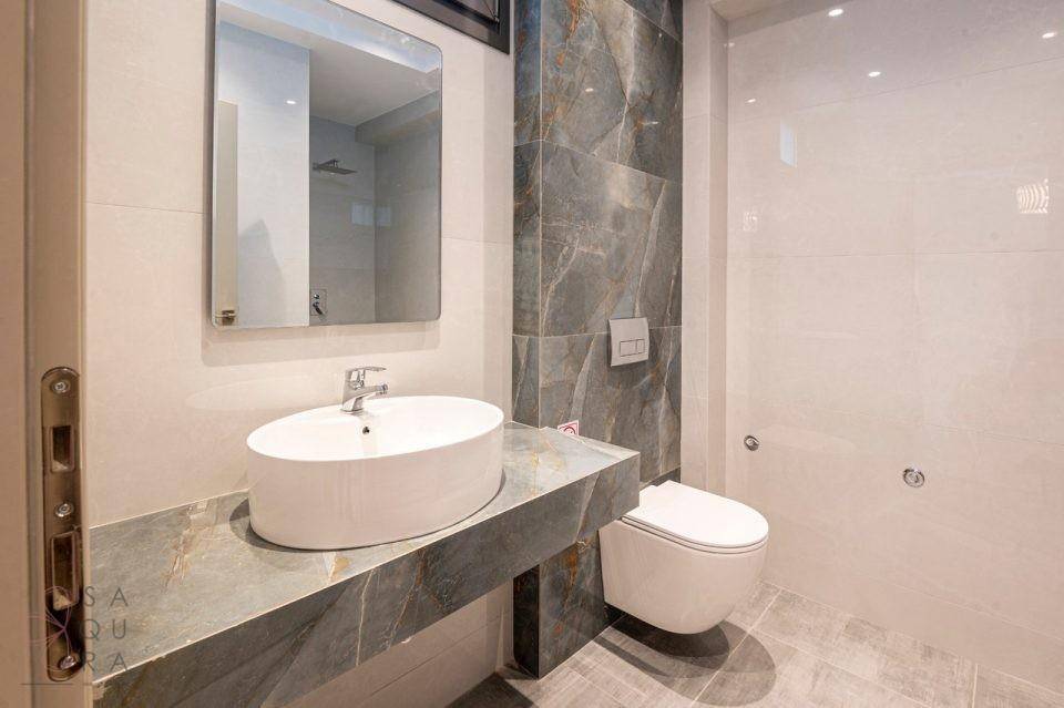 Stilvolles Badezimmer mit modernem Waschbecken, Wand-WC und großformatigen Fliesen.