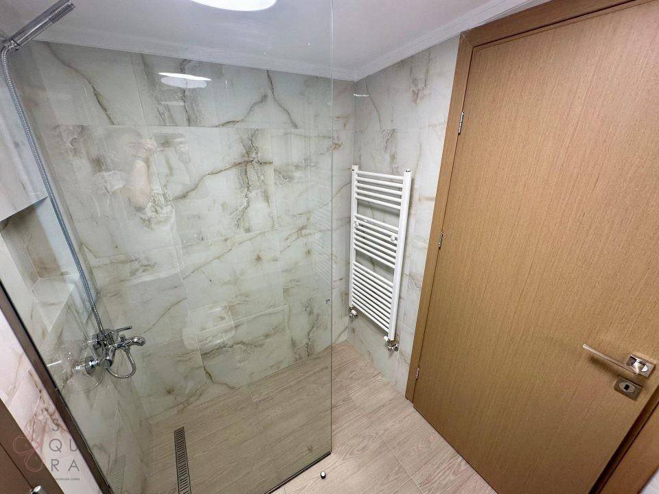 Modernes Badezimmer mit begehbarer Dusche, Marmorfliesen und beheiztem Handtuchhalter.