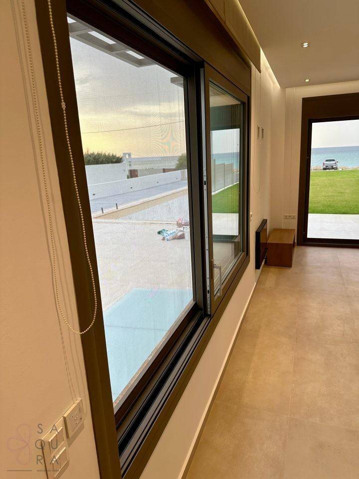 Großes Fenster mit Blick auf den Poolbereich und das Meer, das viel Licht hereinlässt.