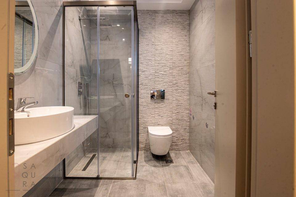 Modernes Badezimmer mit begehbarer Dusche, wandhängendem WC und eleganten grauen Fliesen.