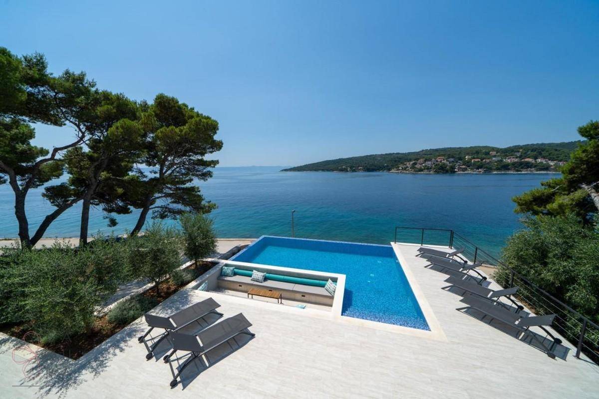 Atemberaubender Infinity-Poolbereich mit Liegestühlen und weitem Blick auf das Meer und die Küste.