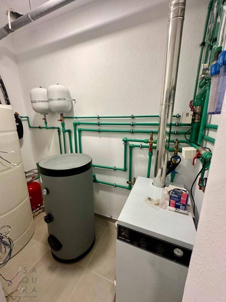 Technikraum mit Heizungsanlage, Warmwasserspeicher und Wasserleitungen.