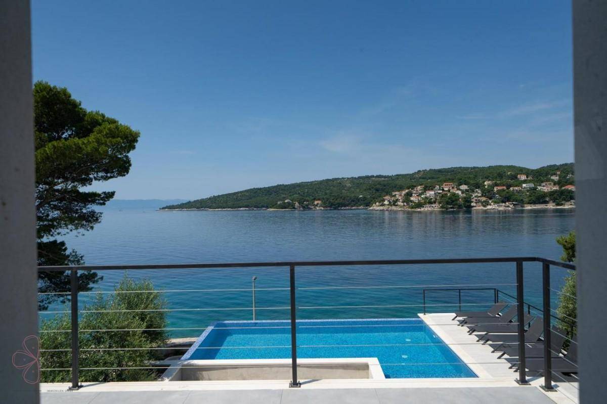 Panoramablick von der Terrasse auf den Pool und das glitzernde Meer mit der gegenüberliegenden Küste.