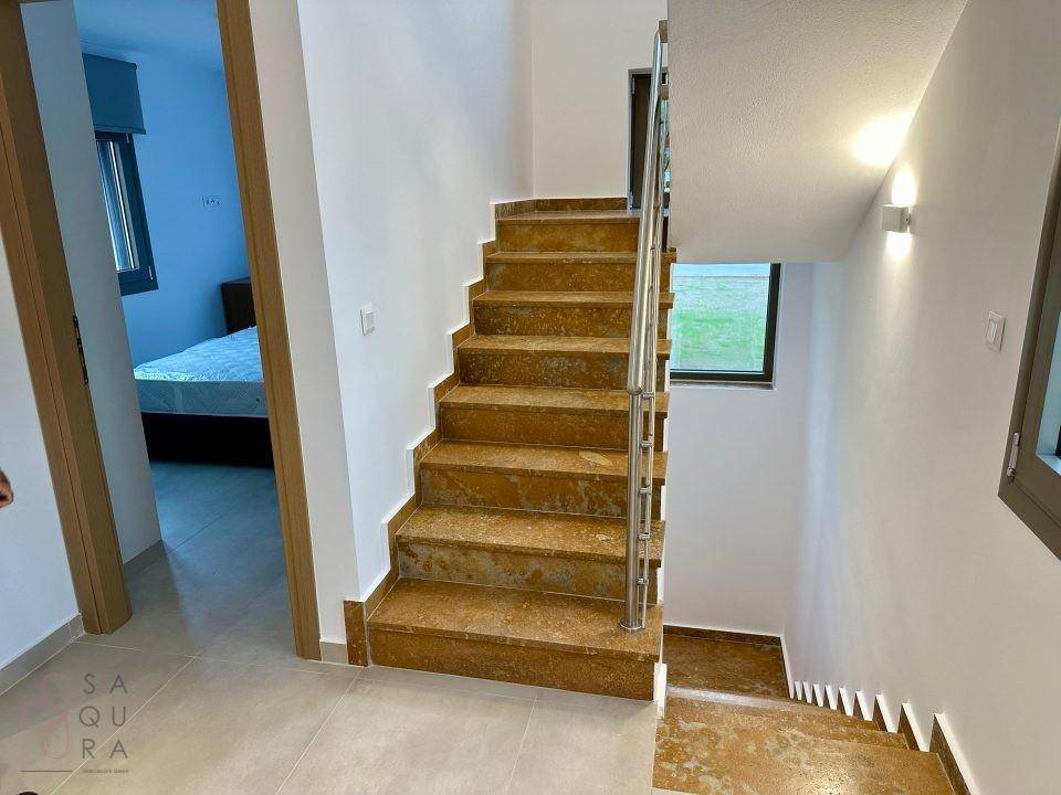 Elegante Steintreppe mit modernem Geländer, die die verschiedenen Etagen des Hauses verbindet.