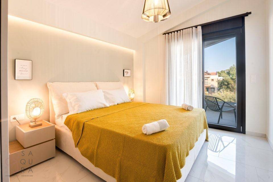 Helles Schlafzimmer mit Doppelbett, gelber Bettwäsche und direktem Balkonzugang.
