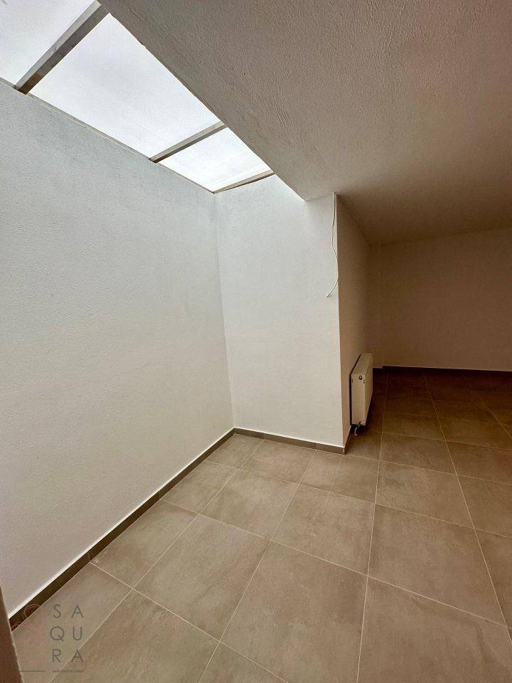 Heller Raum mit Fliesenboden und einem Oberlicht, das natürliches Licht spendet.