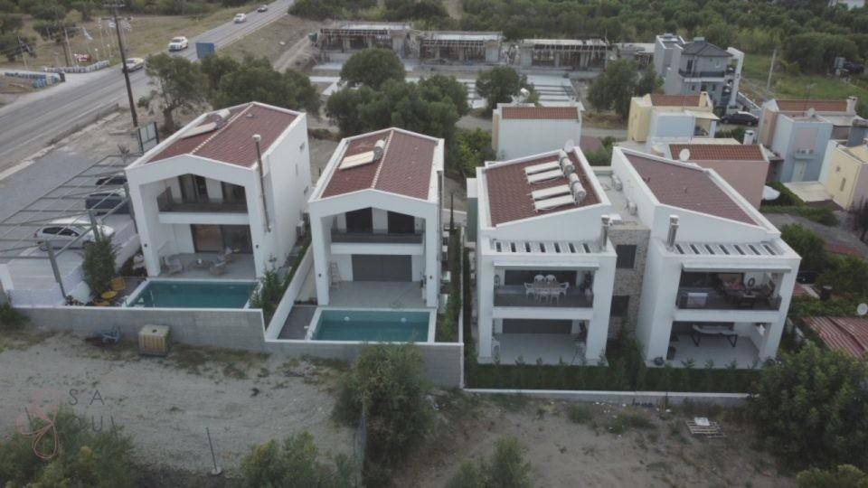 Moderne Neubauten mit Pools und roten Satteldächern in einer Wohnsiedlung.