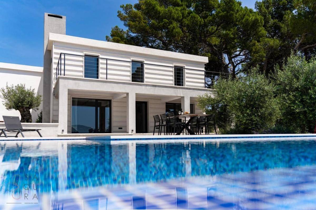 Elegante Villa mit großem Swimmingpool und Essbereich im Freien mit Meerblick.