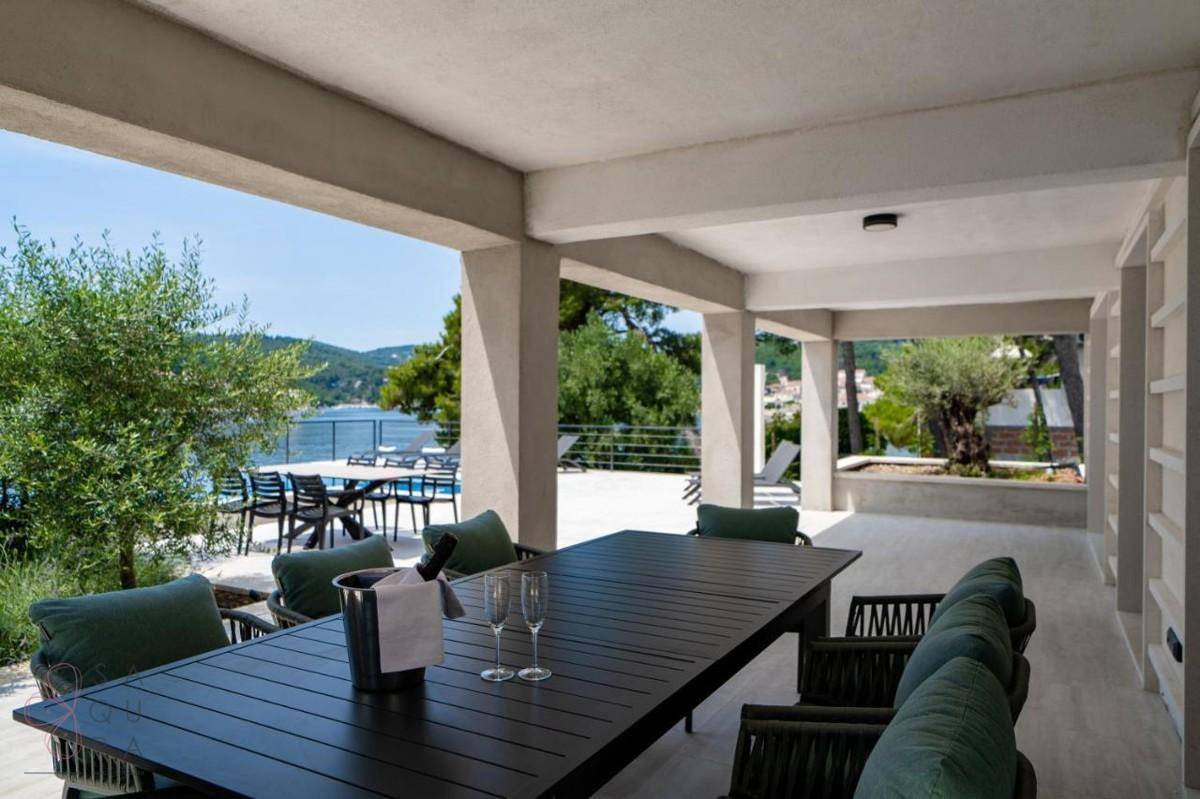 Geräumige überdachte Terrasse mit großem Esstisch und bequemen Stühlen, perfekt für Mahlzeiten im Freien.