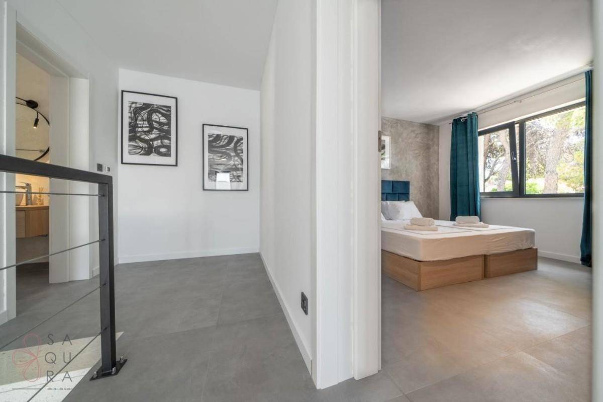 Moderner Flur mit Kunstwerken an der Wand, der zu einem hellen Schlafzimmer führt.