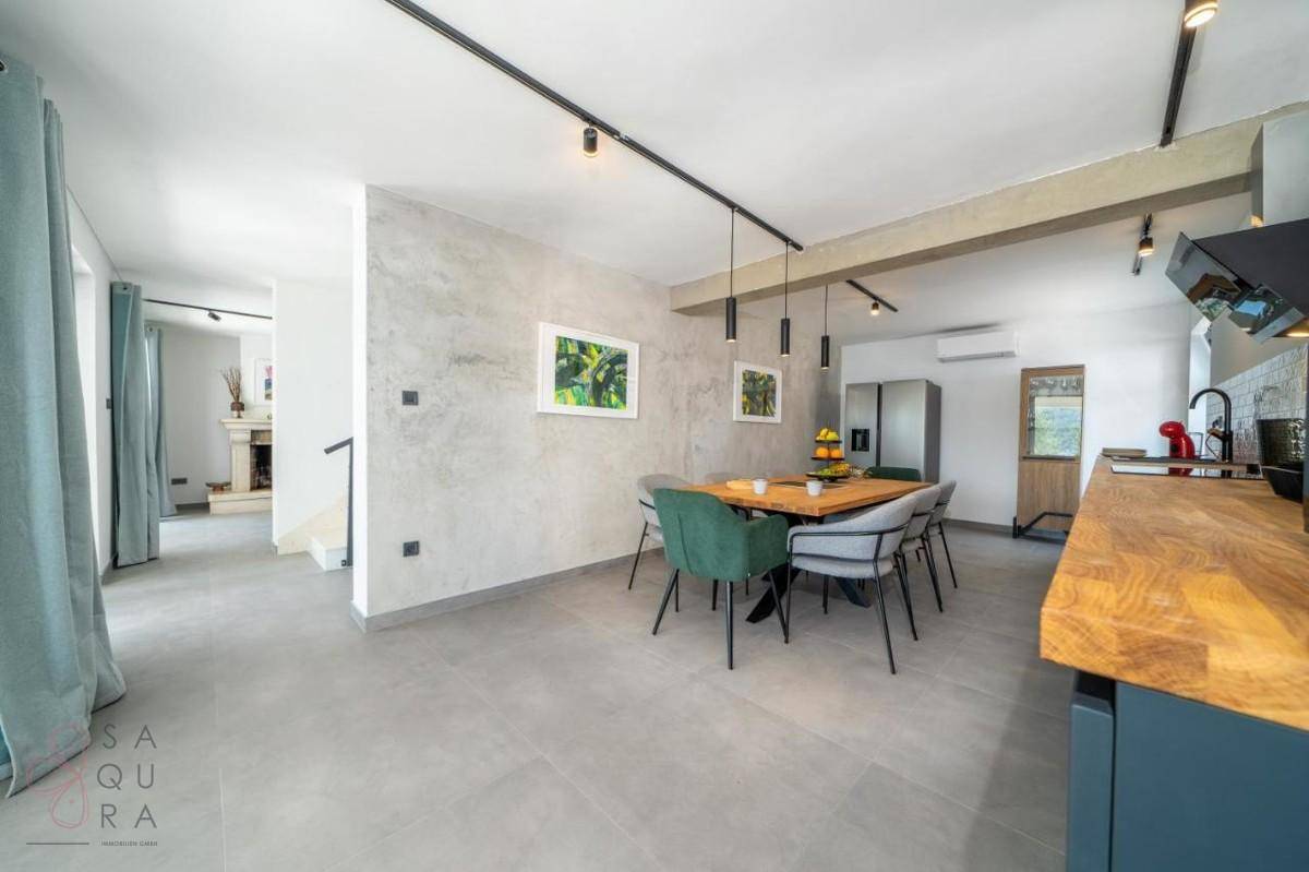 Offener Wohn- und Essbereich mit moderner Küche, großem Esstisch und Blick ins Wohnzimmer.