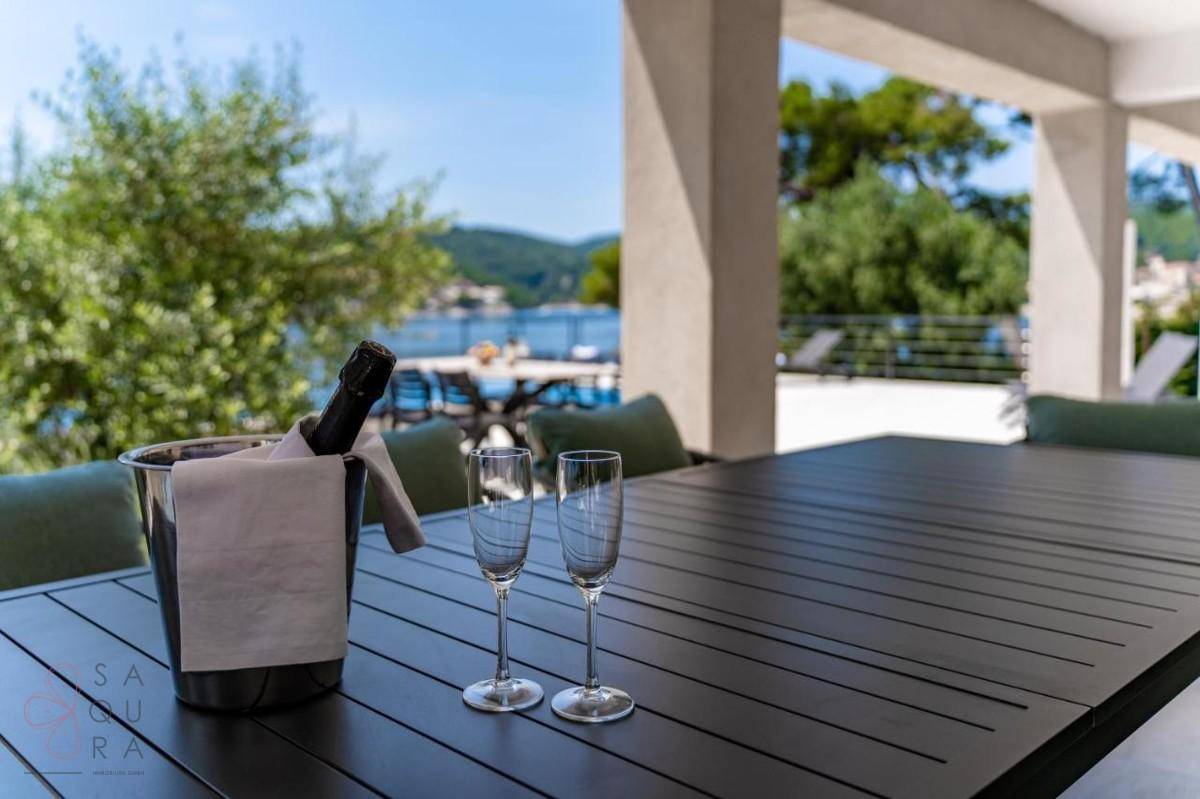 Detailaufnahme des gedeckten Tisches auf der Terrasse mit Champagner und Meerblick im Hintergrund.