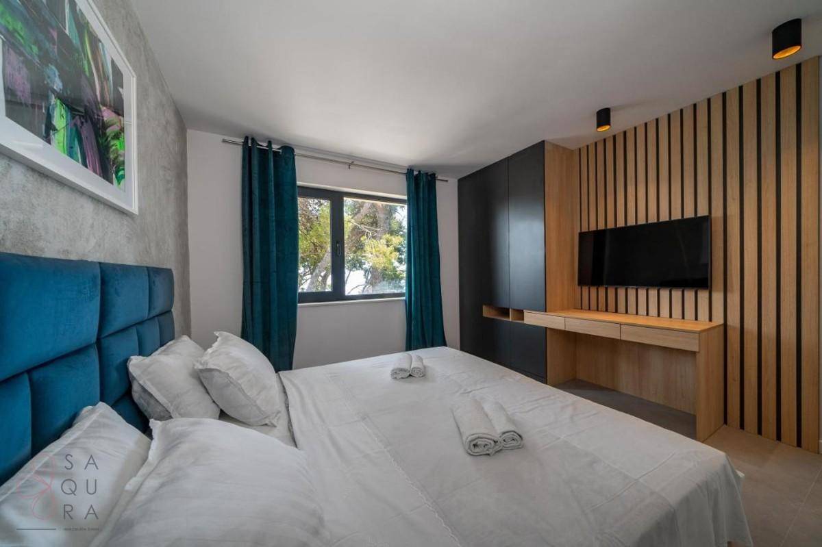 Geräumiges Schlafzimmer mit modernem Design, Holzwandverkleidung und integriertem Schreibtischbereich.