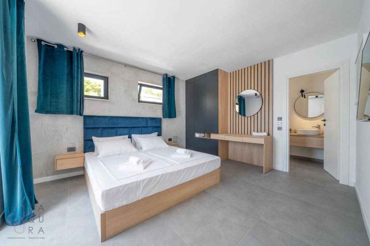 Modernes Schlafzimmer mit Doppelbett, Holzwandverkleidung und offenem Zugang zum Badezimmer.