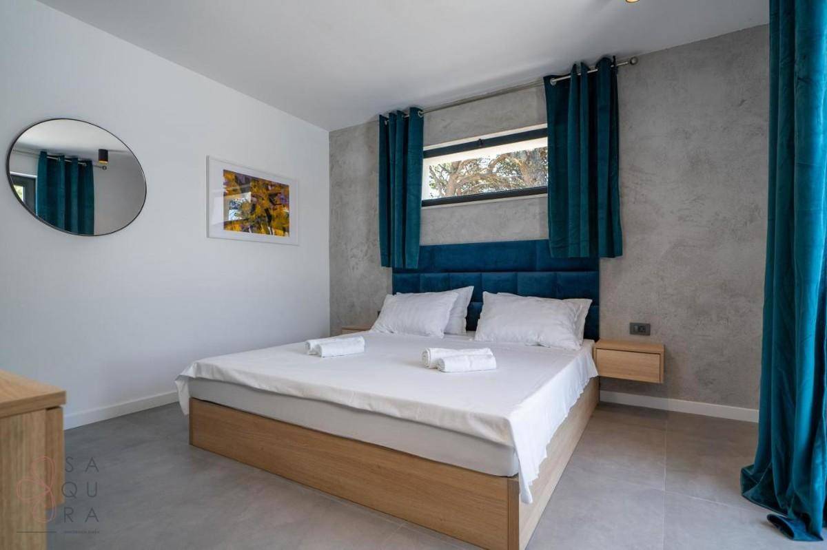 Modernes Schlafzimmer mit Doppelbett, blauen Vorhängen und grauen Fliesenböden.
