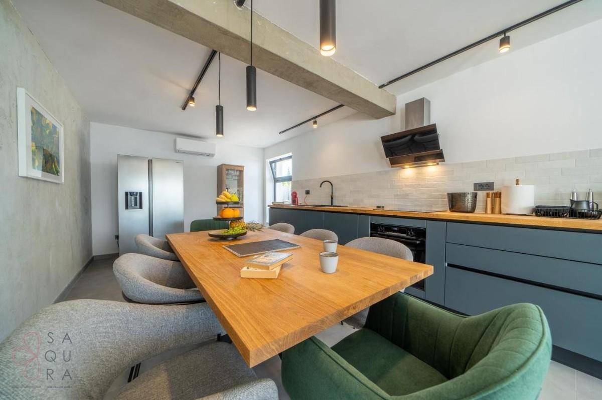 Geräumiger Essbereich mit Holztisch und moderner Küche, ideal für gesellige Runden.