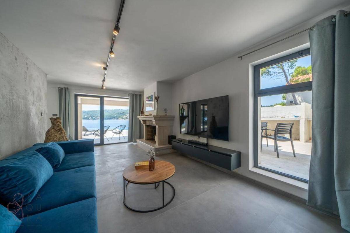Helles Wohnzimmer mit Meerblick, Kamin und Zugang zu einer Außenterrasse.