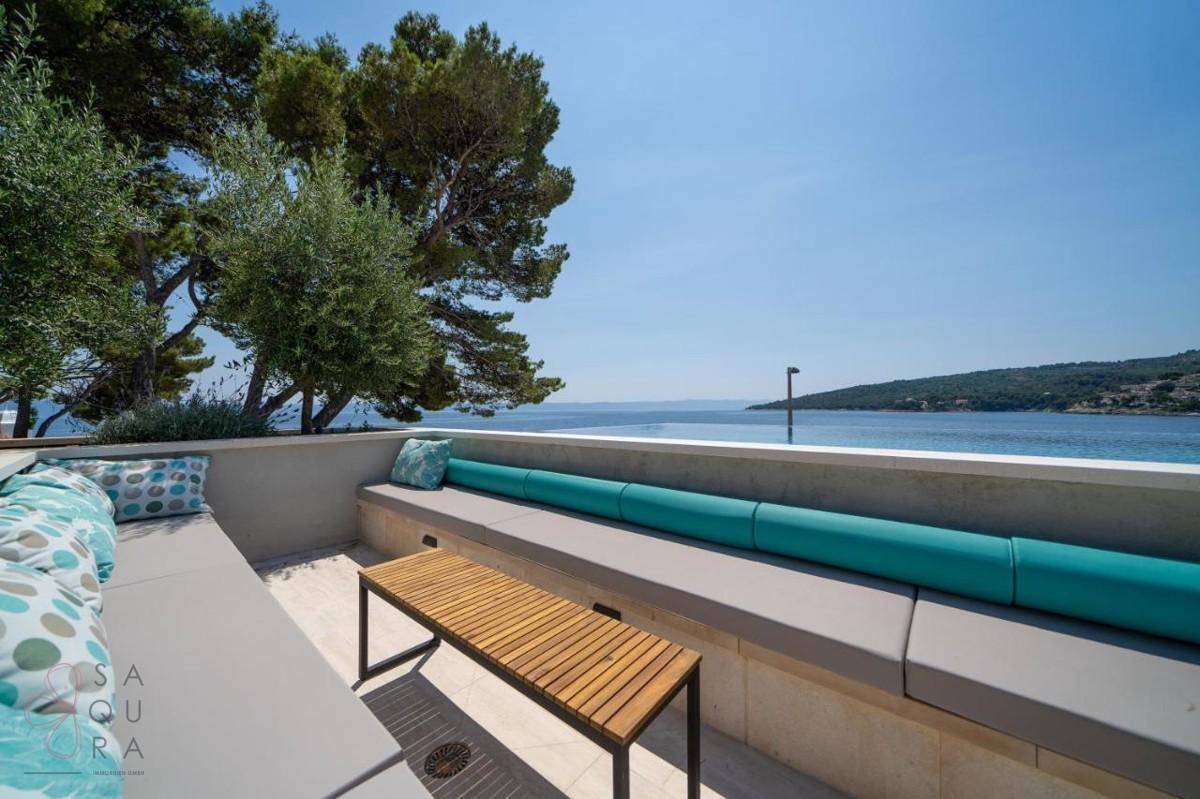 Komfortable Outdoor-Lounge mit Holztisch und Blick auf den Infinity-Pool und das offene Meer.