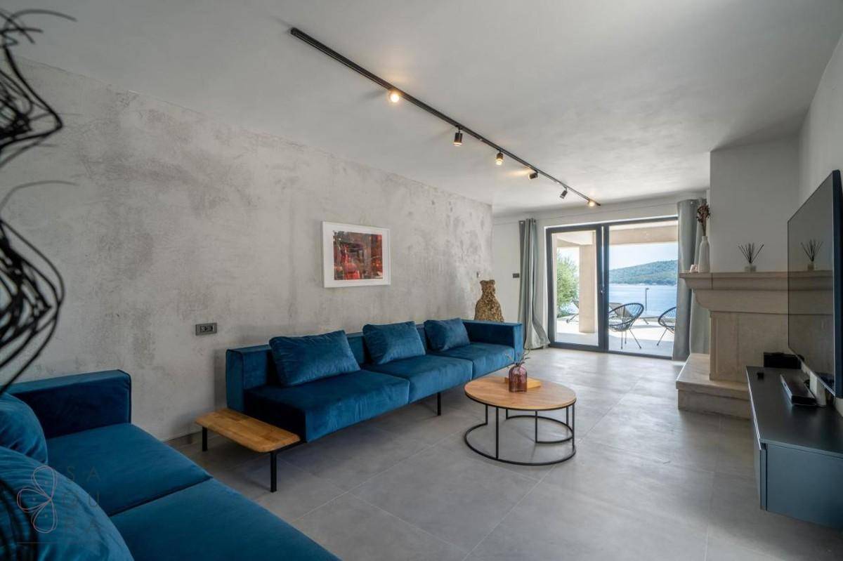 Modernes Wohnzimmer mit bequemen blauen Sofas, Couchtischen und Blick auf die Terrasse.