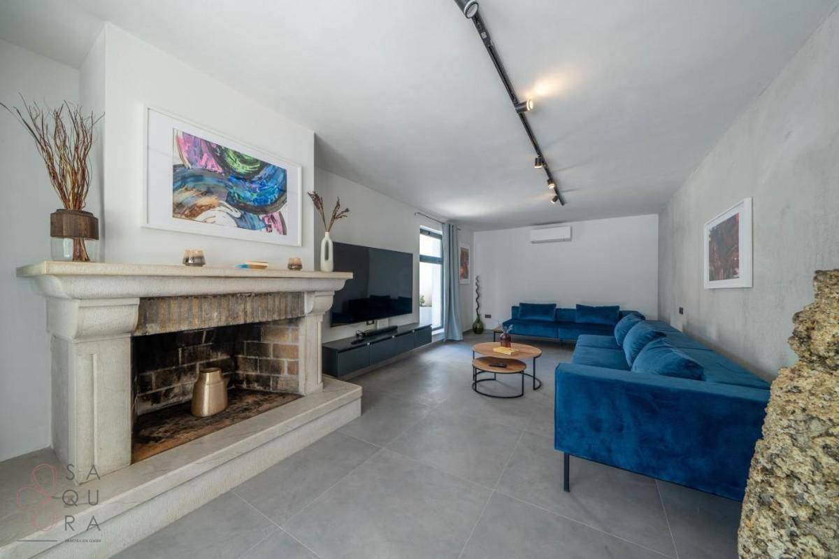 Geräumiges Wohnzimmer mit Kamin, blauen Sofas und moderner Einrichtung, ideal zum Entspannen.