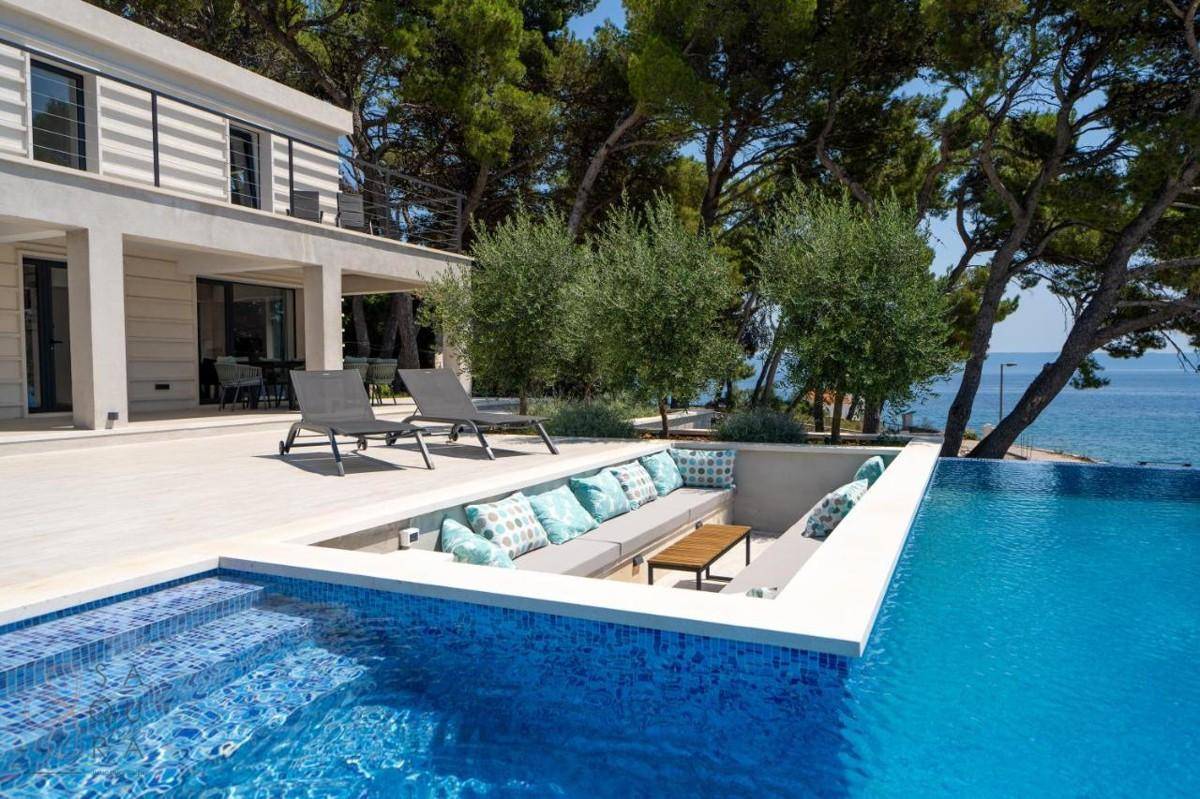 Luxuriöser Poolbereich mit eingelassener Sitzgelegenheit und Panoramablick auf das Meer.
