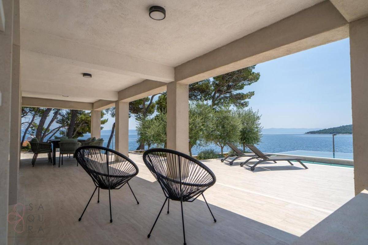 Überdachte Terrasse mit modernen Sitzgelegenheiten und weitem Blick auf das glitzernde Meer.