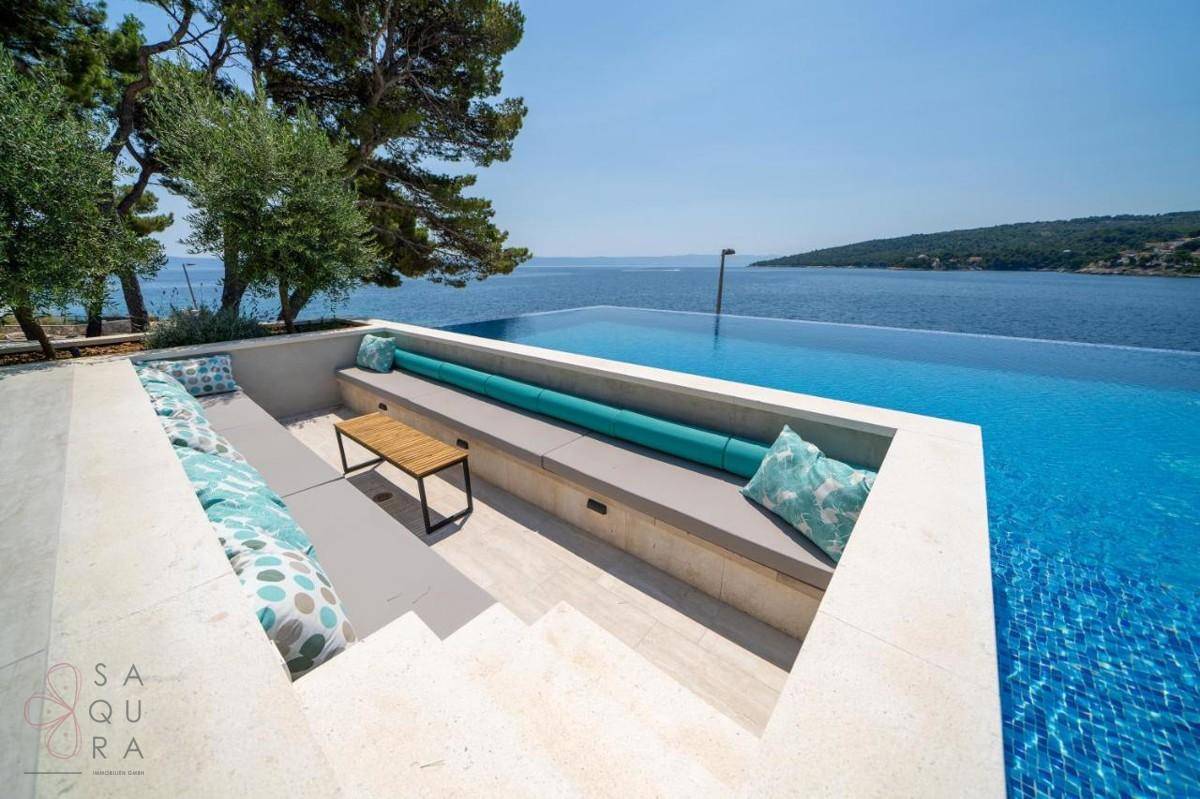 Elegante, versunkene Lounge-Sitzgelegenheit am Pool mit bequemen Kissen und Meerblick.