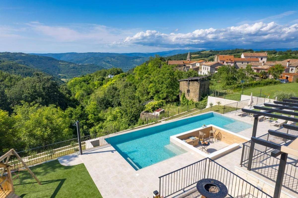 Panoramablick auf die Villa mit Poolbereich und einem charmanten Dorf in der Ferne.