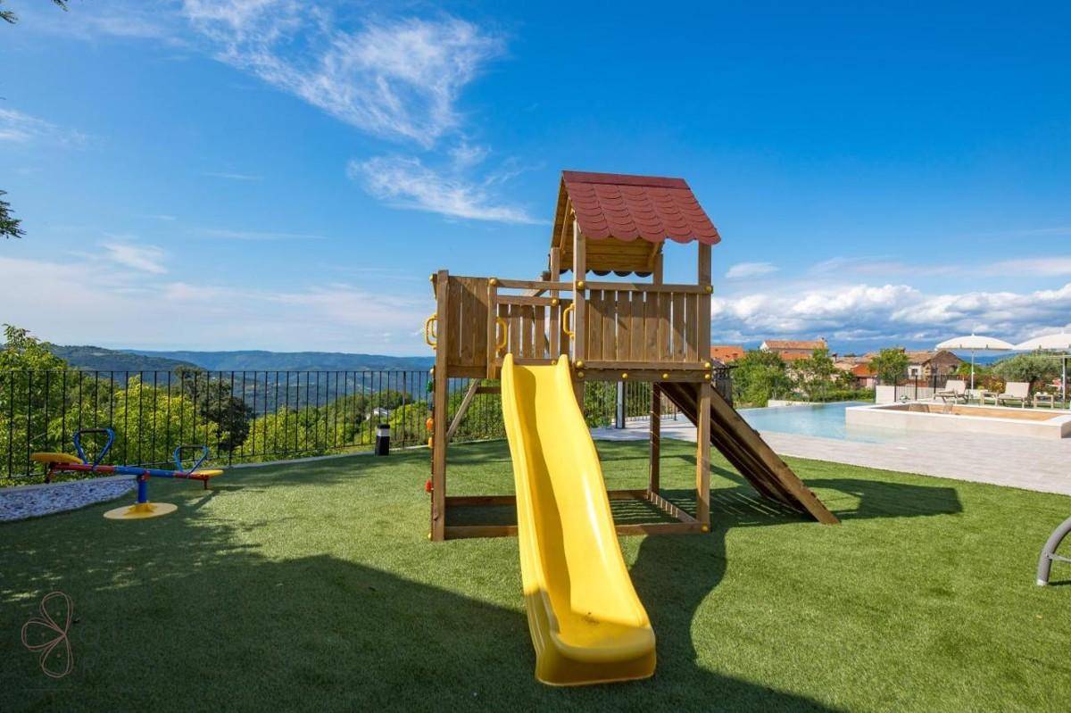 Kinderspielplatz mit Rutsche und Schaukel auf Kunstrasen, mit Blick auf die Landschaft.