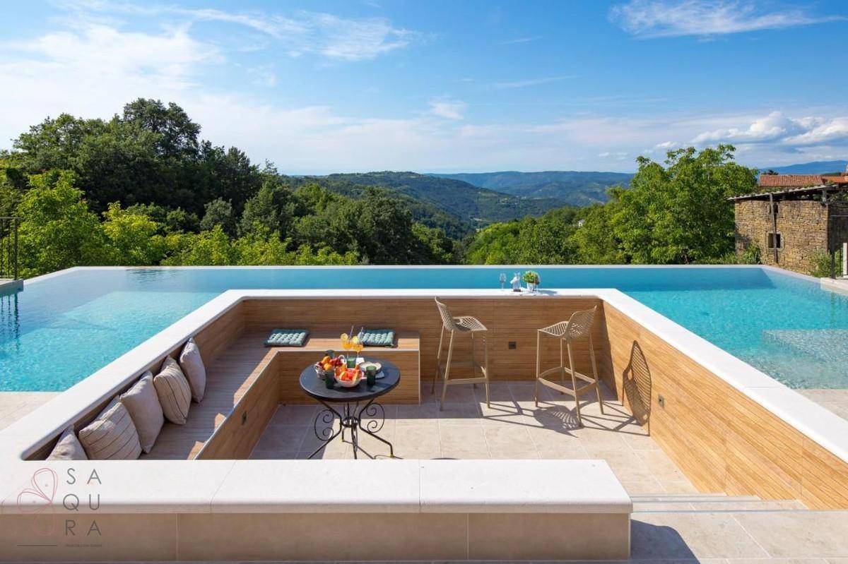 Einzigartiger Poolbereich mit integrierter Lounge und Bar, umgeben von grüner Hügellandschaft.