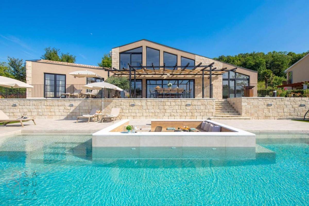 Elegante Villa mit großem Pool, Sonnenterrasse und moderner Architektur unter blauem Himmel.
