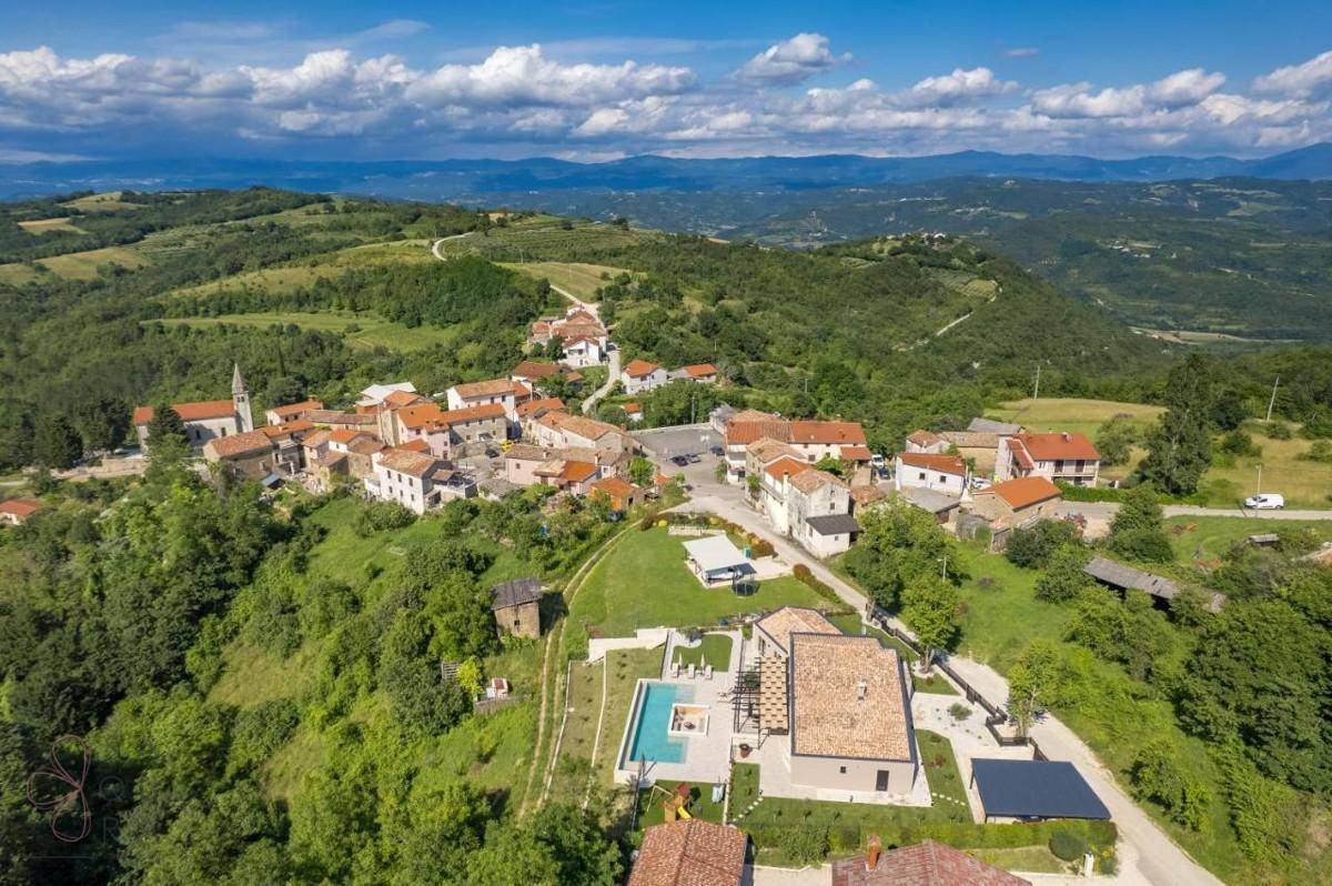 Malerischer Panoramablick auf ein traditionelles Dorf, eingebettet in eine grüne Hügellandschaft.