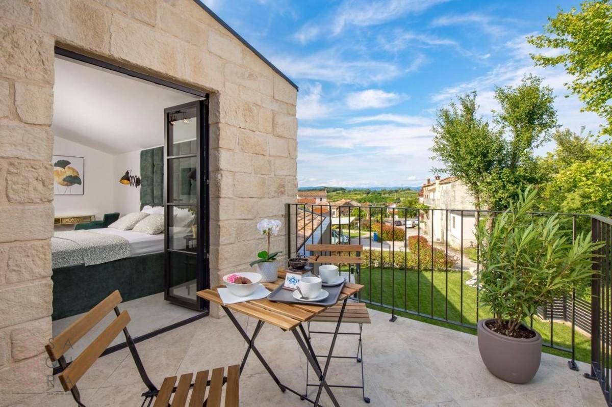 Helles Schlafzimmer mit Zugang zu einem kleinen Balkon und Blick auf die umliegende Landschaft.