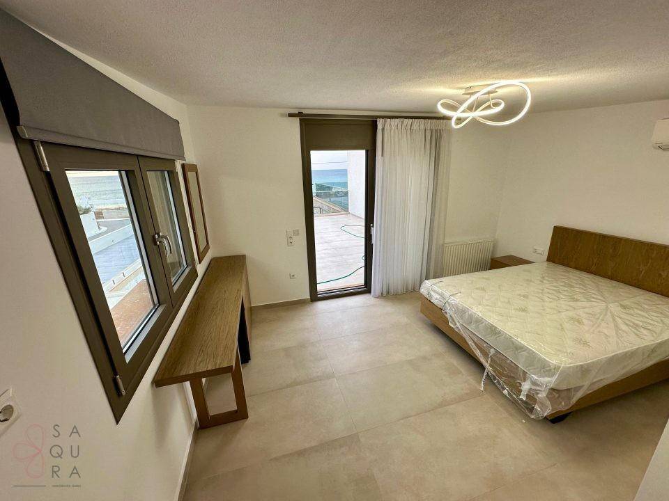 Schlafzimmer mit Meerblick, Zugang zum Balkon und moderner Deckenleuchte.