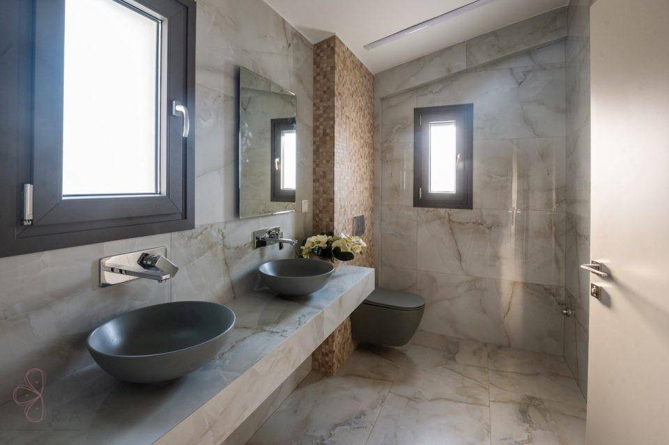 Modernes Badezimmer mit zwei Aufsatzwaschbecken, Wand-WC und Fenstern für Tageslicht.