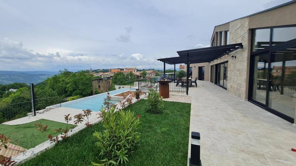 Seitlicher Blick auf die Villa mit Poolbereich, Rasenfläche und weitem Blick auf die Landschaft.