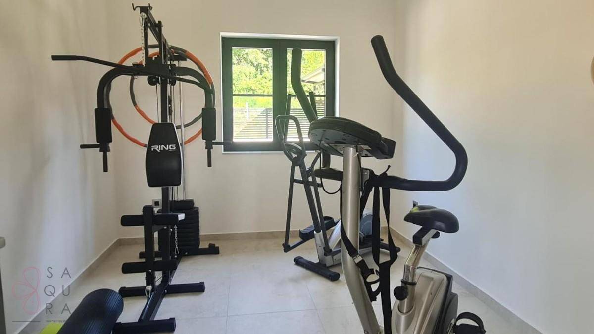 Privater Fitnessraum mit verschiedenen Trainingsgeräten und einem Fenster für natürliches Licht.