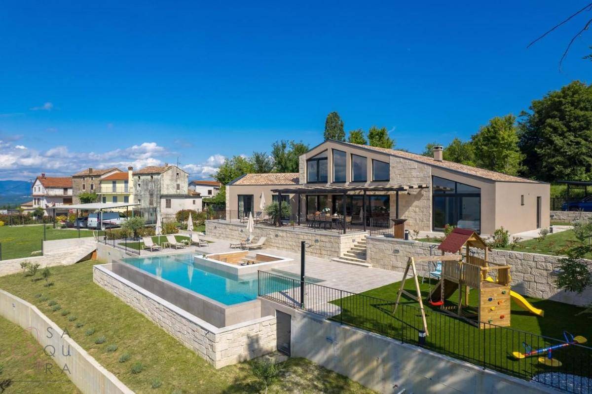 Moderne Villa mit großem Pool, Sonnenterrasse und Kinderspielplatz, umgeben von Natur.
