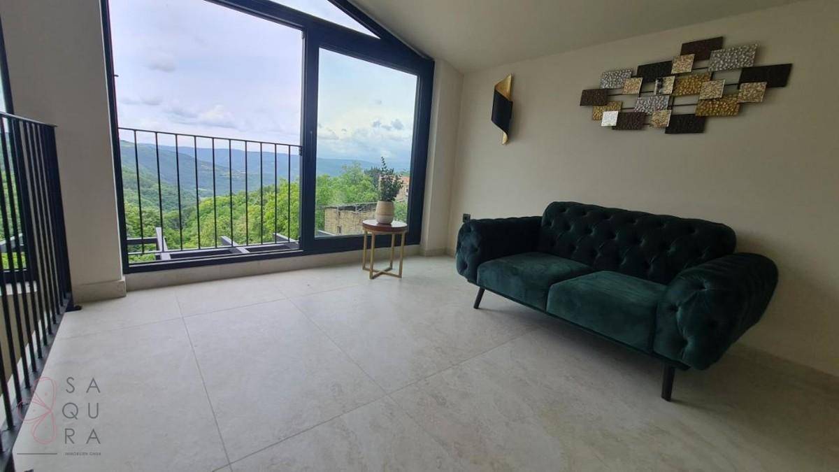 Gemütlicher Loungebereich auf der Galerie mit dunkelgrünem Sofa und weitem Panoramablick auf die Landschaft.